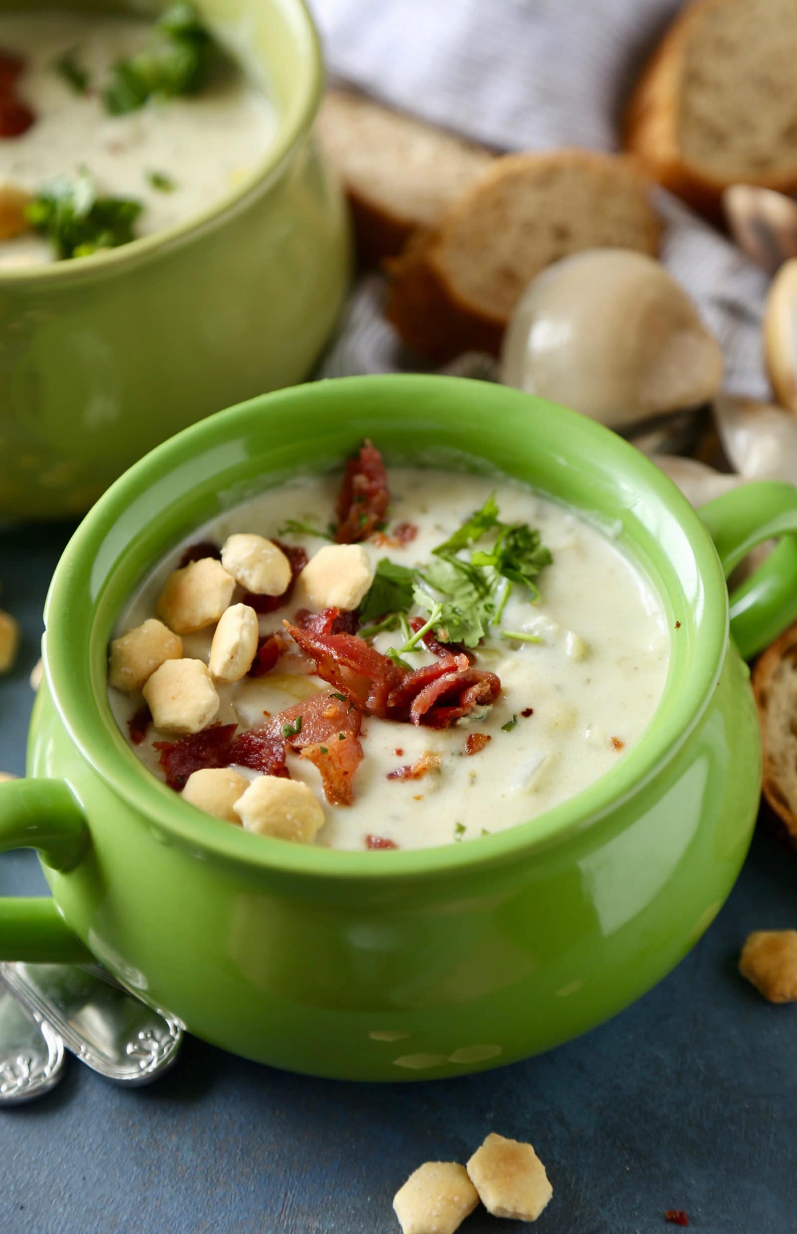 Clam chowder in green bowl with bacon and oyster crackers