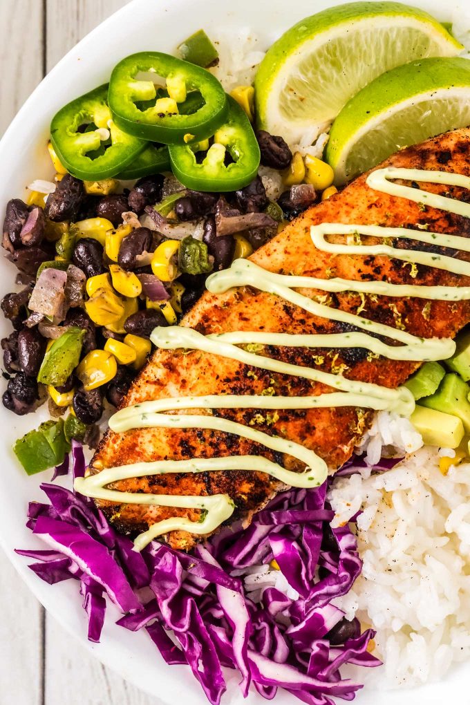 fish taco bowls drizzled with avocado cream in a white bowl