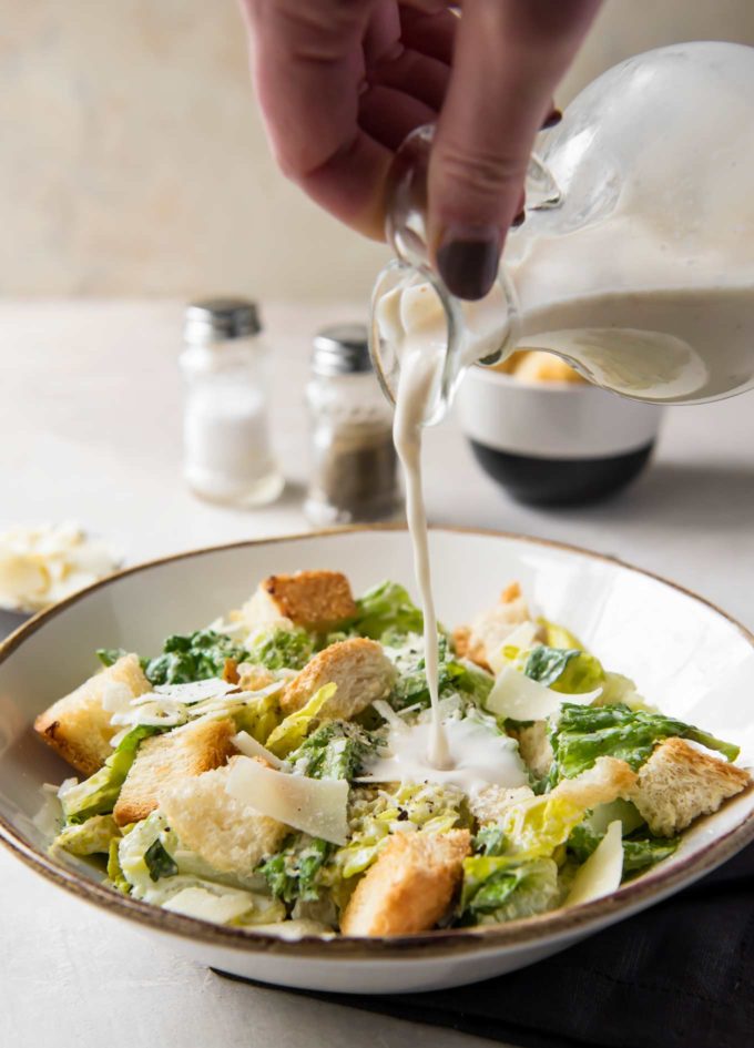 Pouring homemade caesar salad dressing