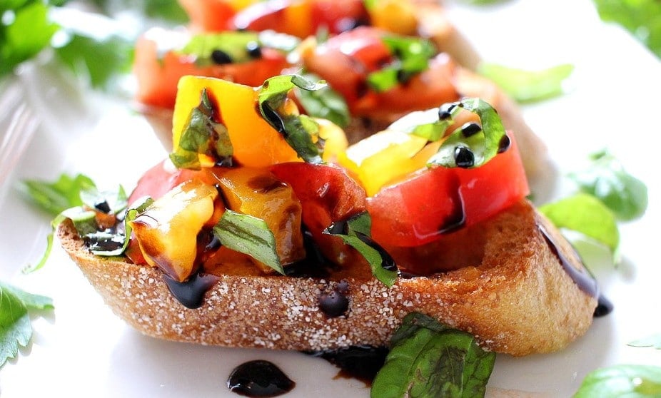 The Chunky Chef | Classic bruschetta gets a gourmet twist by using sweet heirloom tomatoes, basil, fresh mozzarella, and drizzled with a decadent balsamic reduction glaze!