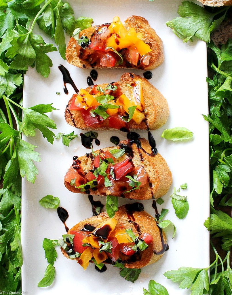 The Chunky Chef | A recipe for classic bruschetta gets a gourmet twist by using sweet heirloom tomatoes, basil, fresh mozzarella, and drizzled with a decadent balsamic reduction glaze!