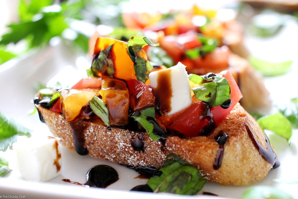 The Chunky Chef | A recipe for classic bruschetta gets a gourmet twist by using sweet heirloom tomatoes, basil, fresh mozzarella, and drizzled with a decadent balsamic reduction glaze!