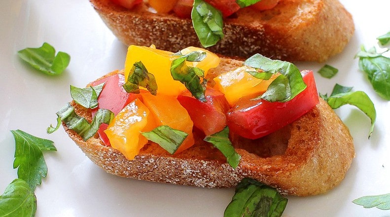 The Chunky Chef | A recipe for classic bruschetta gets a gourmet twist by using sweet heirloom tomatoes, basil, fresh mozzarella, and drizzled with a decadent balsamic reduction glaze!