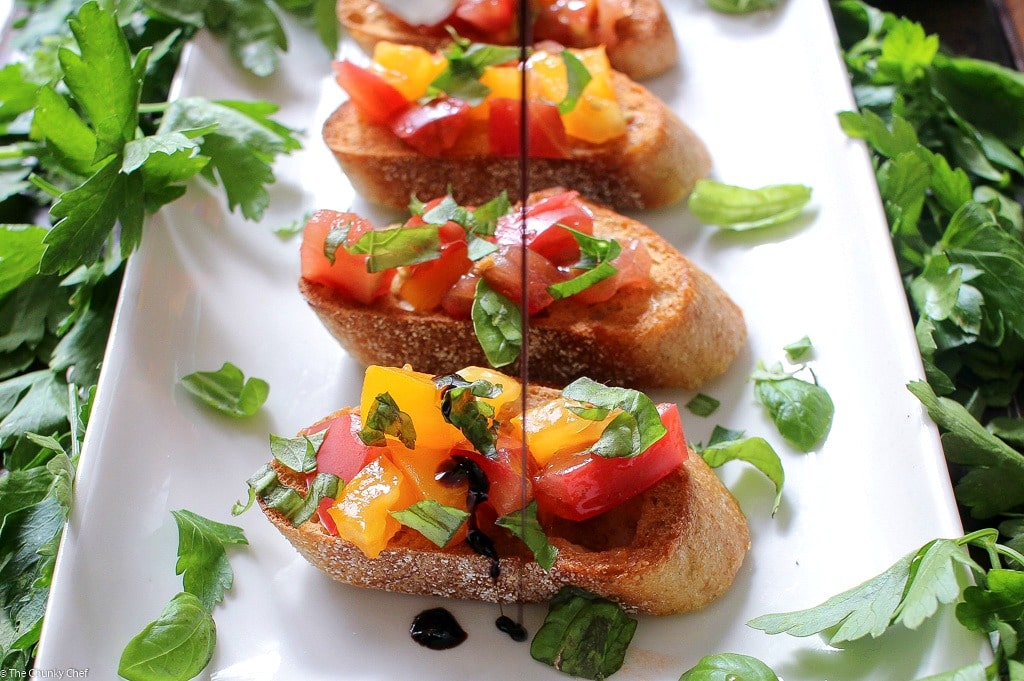 The Chunky Chef | A recipe for classic bruschetta gets a gourmet twist by using sweet heirloom tomatoes, basil, fresh mozzarella, and drizzled with a decadent balsamic reduction glaze!