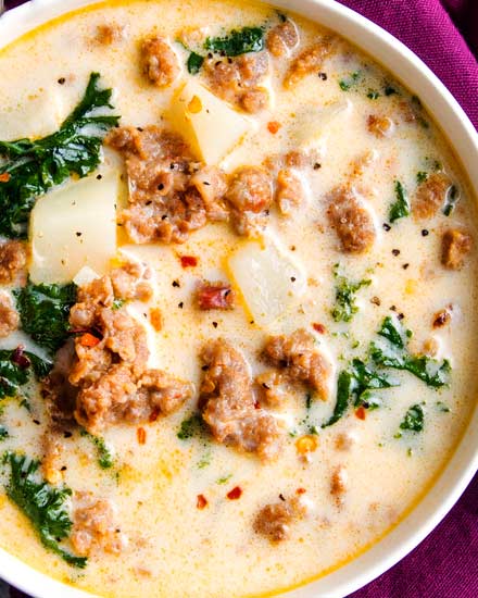 The BEST copycat zuppa toscana soup, made with spicy crumbled sausage, silky potatoes, and an ultra creamy broth.  Bacon and kale put the finishing touch on this Olive Garden copycat recipe! #soup #souprecipe #copycat #zuppatoscana #olivegarden #slowcooker #crockpot #instantpot #pressurecooker #easyrecipe #weeknightmeal