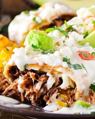 Tortillas stuffed with tender, spicy, slow cooked spiced beef (barbacoa-style), fried to crunchy perfection, then smothered in a velvety smooth white queso! Great meal to use up leftovers too! #beef #chimichangas #mexican #easyrecipe #dinner #barbacoa #queso #cheese #smothered