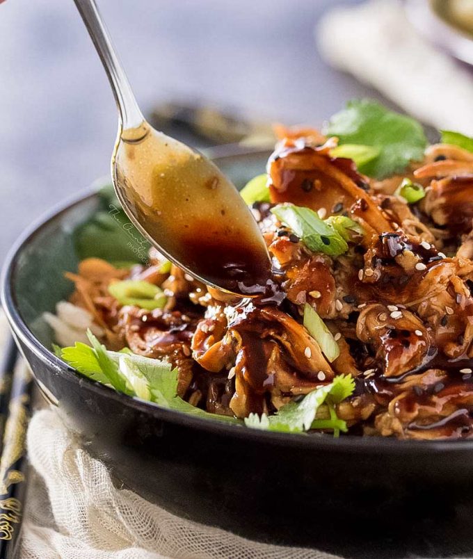 spooning honey garlic sauce over shredded chicken