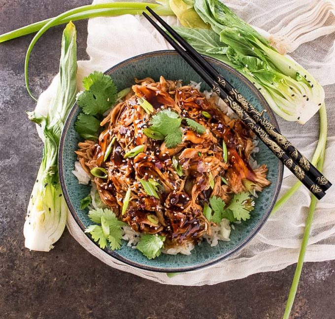 Overhead view of shredded asian chicken in bowl with chopsticks