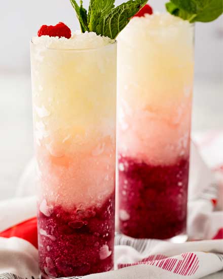Three types of sweet wine are frozen, blended with simple syrup, and layered to create a drink that's every bit as delicious as it is beautiful! #slush #slushy #slushie #wine #ombre #valentinesday #frozendrink #mothersday #cocktail #icy