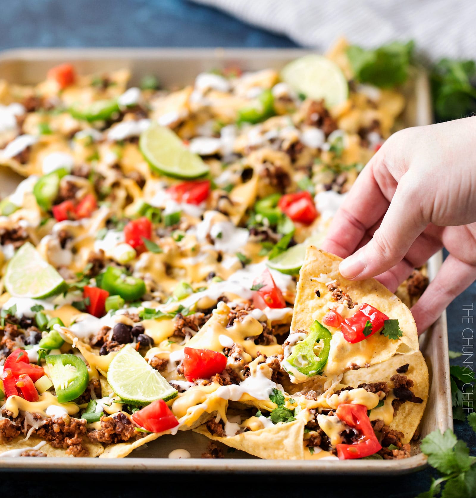 Sheet Pan Beef and Black Bean Nachos | These sheet pan nachos are sure to be a crowd pleaser! Layer after layer of mouthwatering flavor, smothered with a jalapeño cheese sauce and loaded with classic nacho toppings! | http://thechunkychef.com