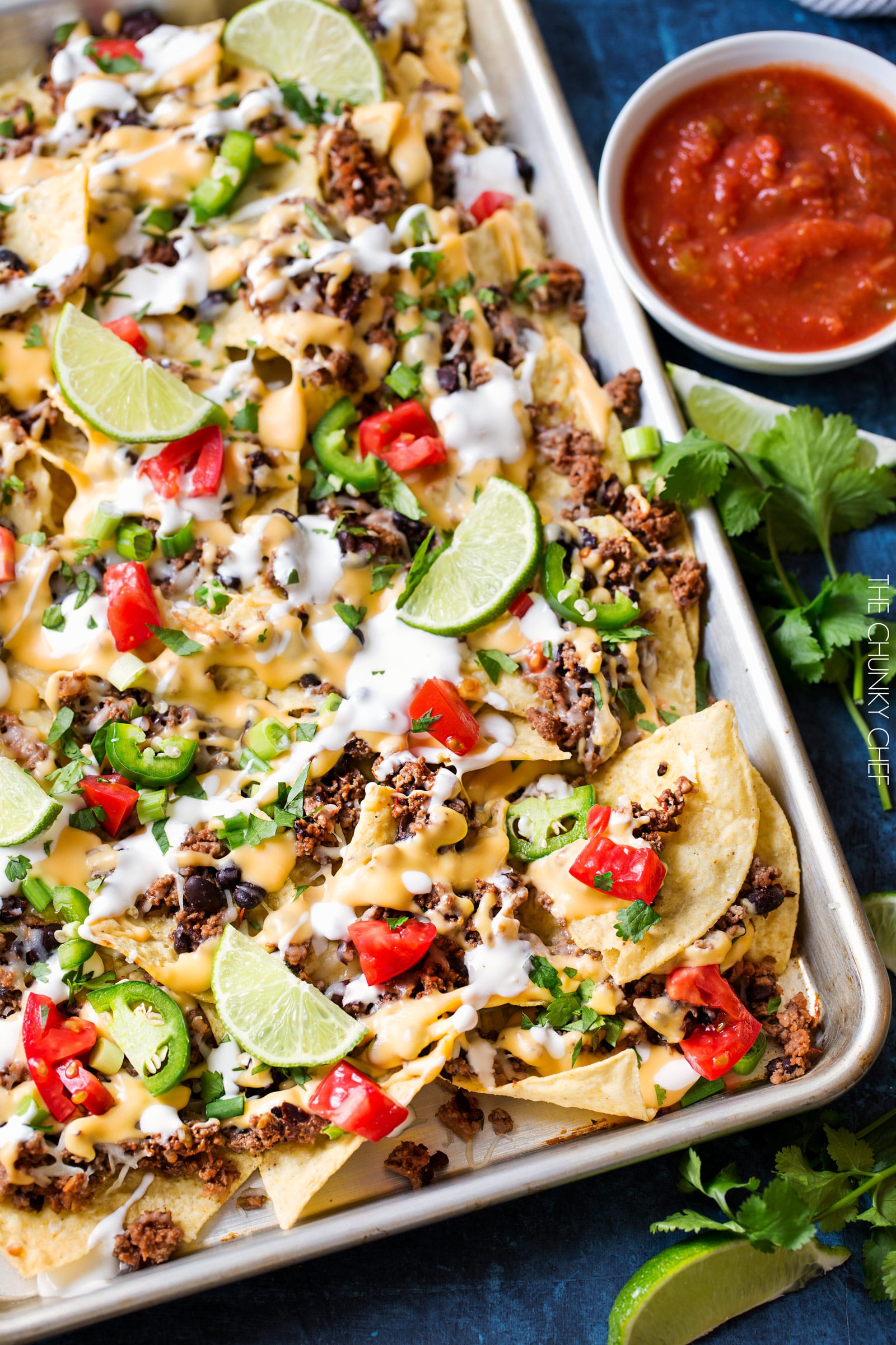 Sheet Pan Beef and Black Bean Nachos | These sheet pan nachos are sure to be a crowd pleaser! Layer after layer of mouthwatering flavor, smothered with a jalapeño cheese sauce and loaded with classic nacho toppings! | http://thechunkychef.com