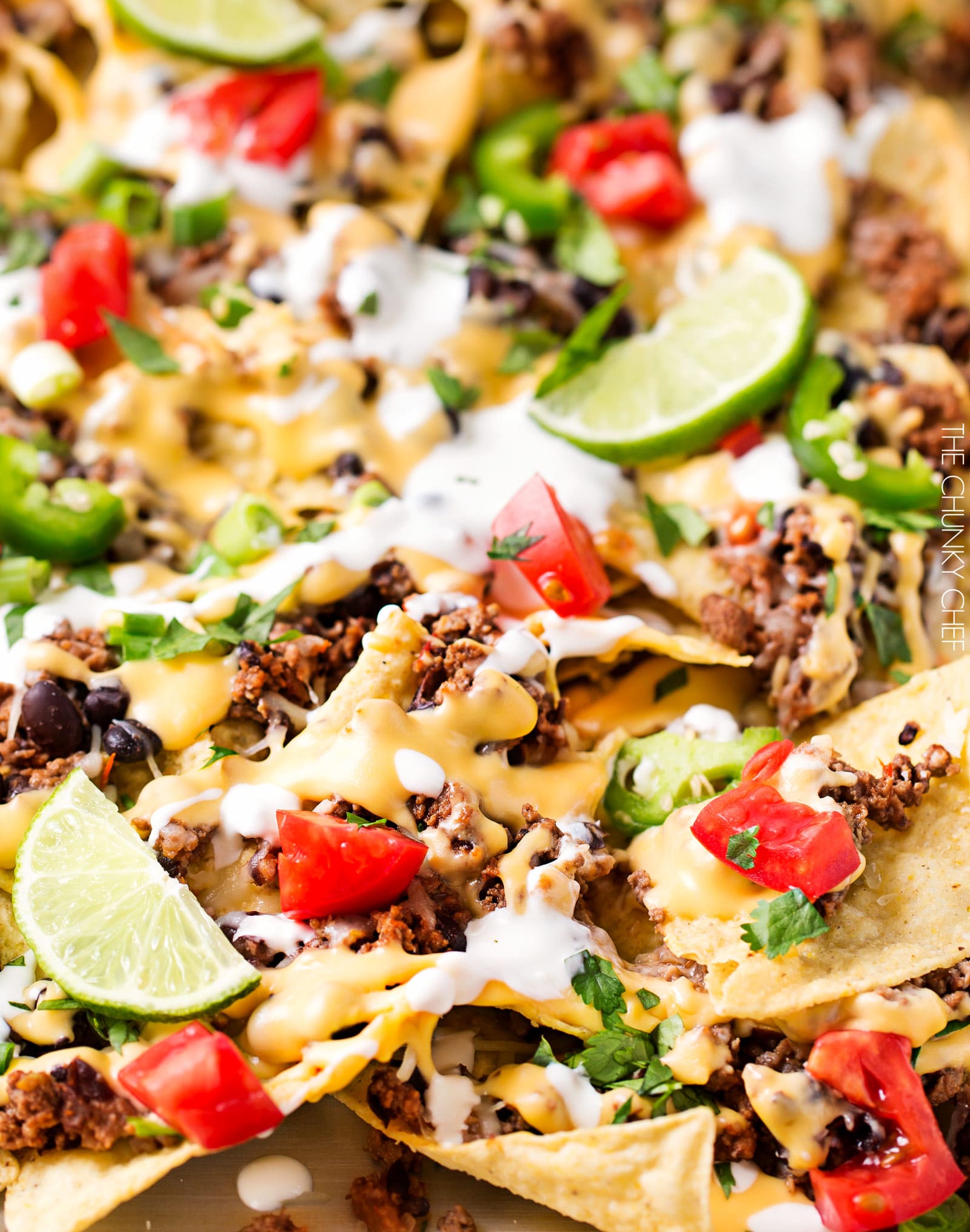 Sheet Pan Beef and Black Bean Nachos | These sheet pan nachos are sure to be a crowd pleaser! Layer after layer of mouthwatering flavor, smothered with a jalapeño cheese sauce and loaded with classic nacho toppings! | http://thechunkychef.com