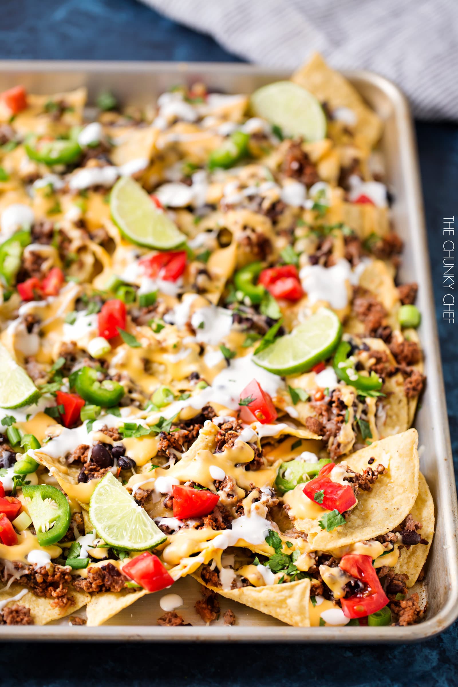 Sheet Pan Beef and Black Bean Nachos | These sheet pan nachos are sure to be a crowd pleaser! Layer after layer of mouthwatering flavor, smothered with a jalapeño cheese sauce and loaded with classic nacho toppings! | http://thechunkychef.com