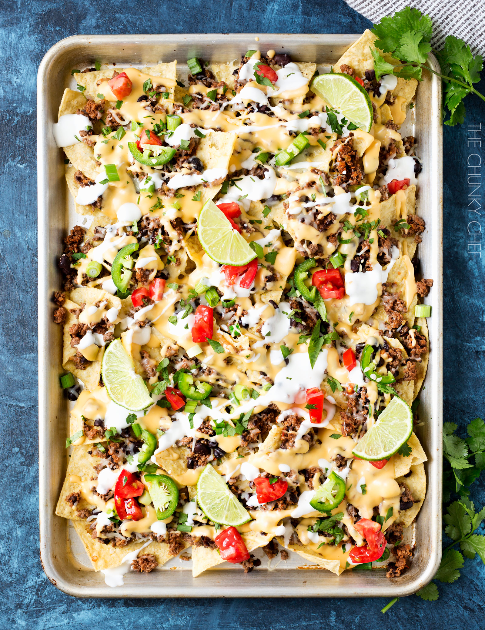 Sheet Pan Beef and Black Bean Nachos | These sheet pan nachos are sure to be a crowd pleaser! Layer after layer of mouthwatering flavor, smothered with a jalapeño cheese sauce and loaded with classic nacho toppings! | http://thechunkychef.com