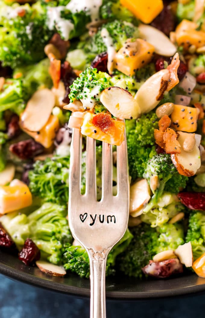 Bite of broccoli salad on fork that says yum