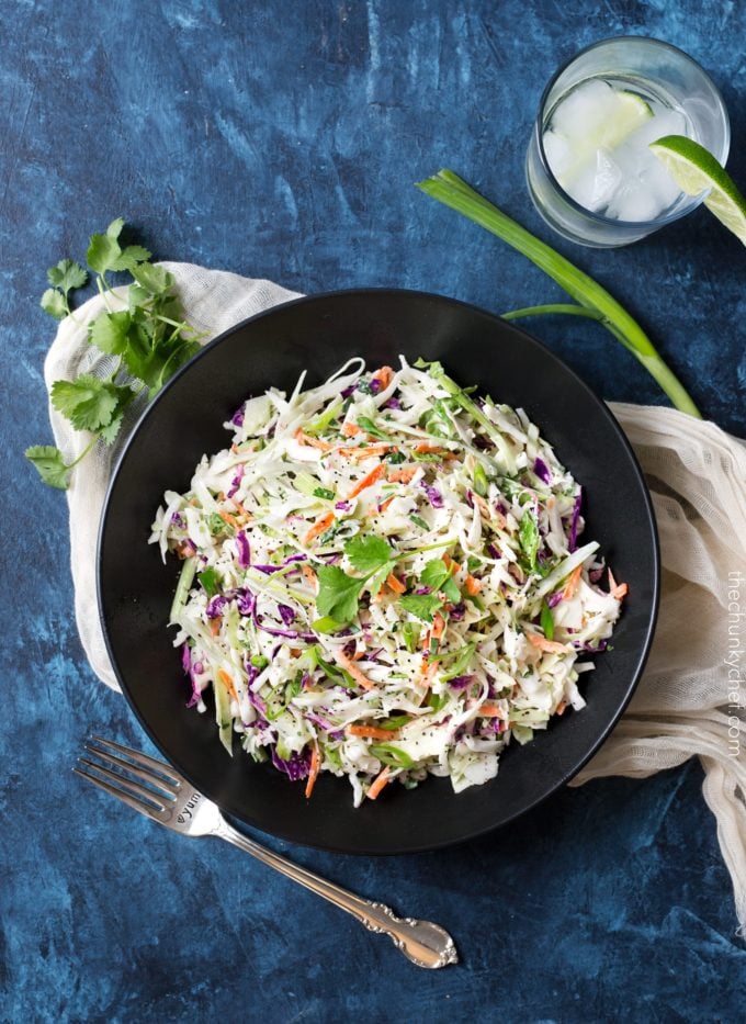 overhead photo of a bowl of tequila lime coleslaw with a rocks glass of tequila near it.