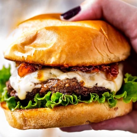 hand holding a cheeseburger topped with bacon jam