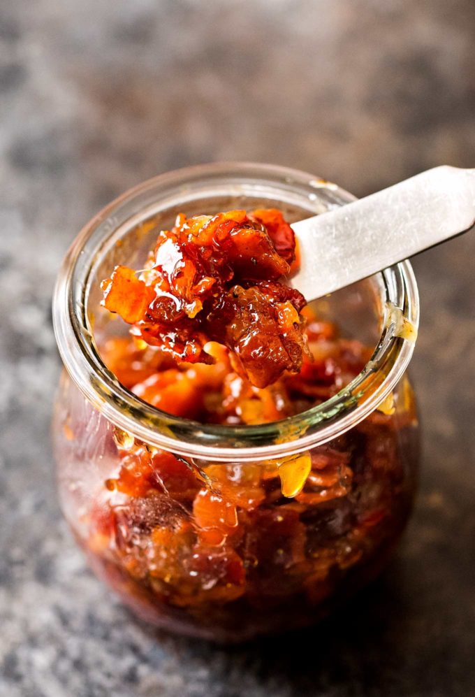 sticky bacon jam on butter knife over a glass jar