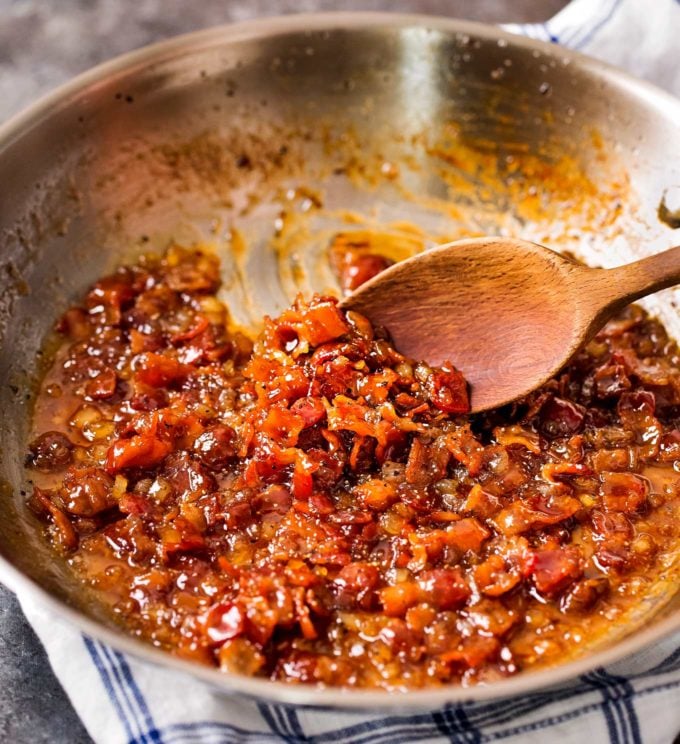 stirring bacon jam in a stainless steel skillet