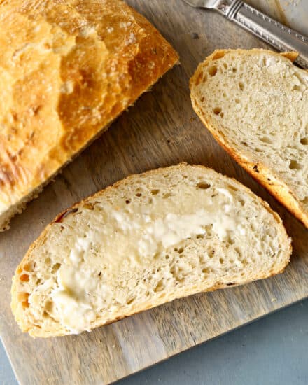 no knead bread slices on cutting board with butter