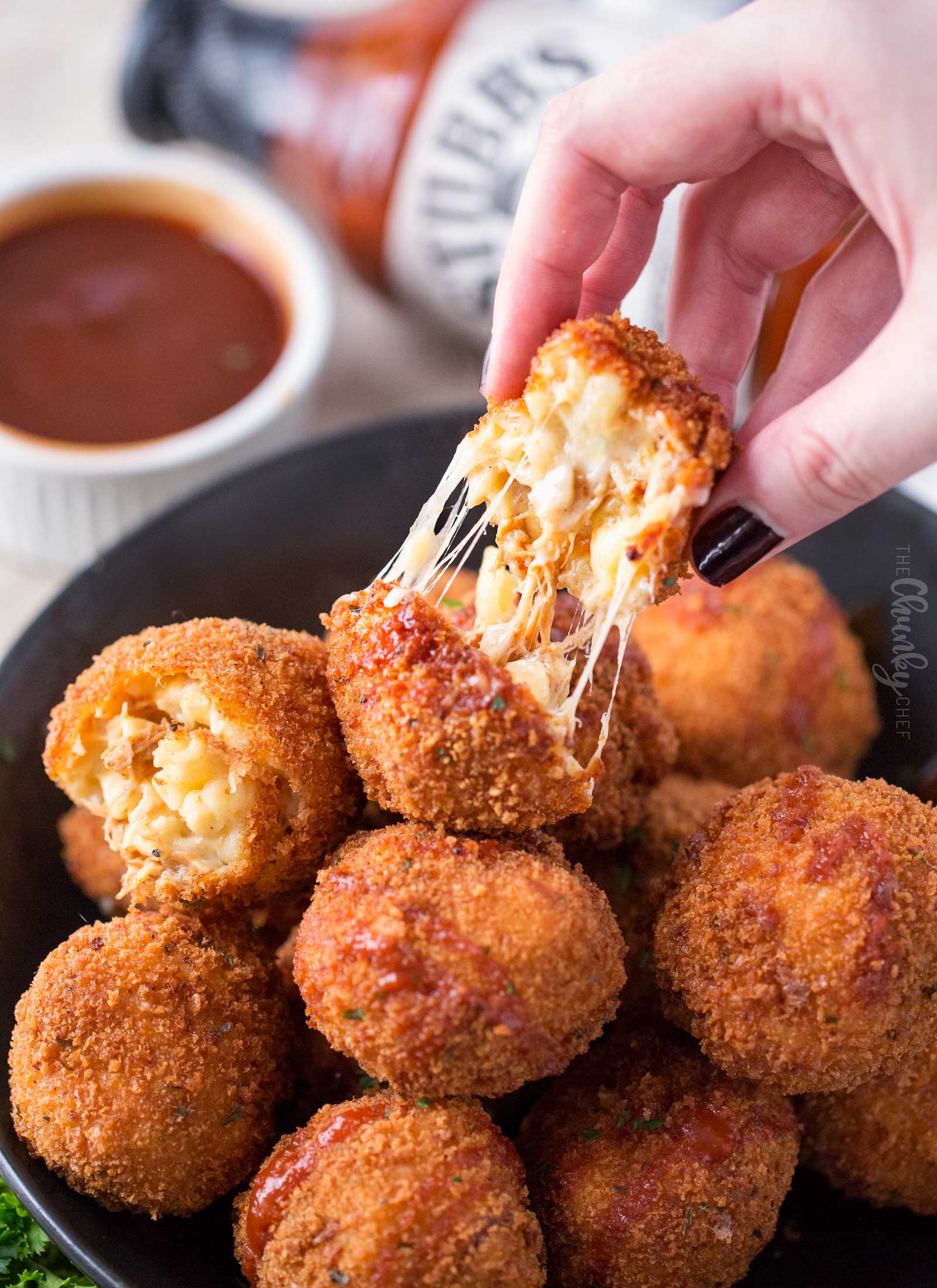 Picture of fried mac and cheese bite being pulled apart with gooey cheese
