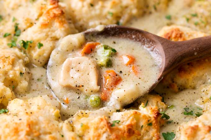 Homestyle Chicken and Biscuits | This Midwest and Southern comfort food recipe is made of savory chicken in rich cream sauce with vegetables, topped with fluffy Parmesan cheese drop biscuits, and baked until bubbly and perfect! | https://thechunkychef.com | #comfortfood #chickenandbiscuits #fromscratch #homestyle #chickenrecipe #dropbiscuits #easyrecipes