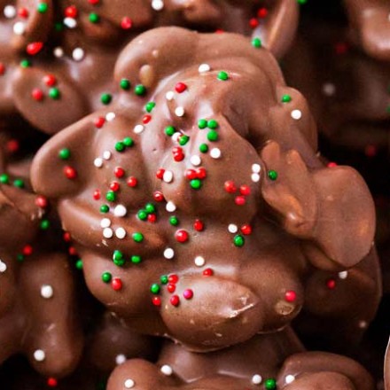 Easy Christmas Crockpot Candy | The easiest homemade candy ever!  Just 4 simple ingredients, a slow cooker, and some holiday sprinkles... and you'll love the chocolate peanut clusters! | The Chunky Chef | #homemadecandy #crockpotcandy #peanutclusters #chocolatecandy #holidaybaking #candyrecipes