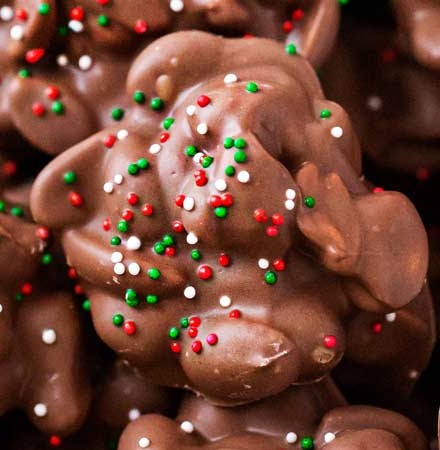 Easy Christmas Crockpot Candy | The easiest homemade candy ever!  Just 4 simple ingredients, a slow cooker, and some holiday sprinkles... and you'll love the chocolate peanut clusters! | The Chunky Chef | #homemadecandy #crockpotcandy #peanutclusters #chocolatecandy #holidaybaking #candyrecipes