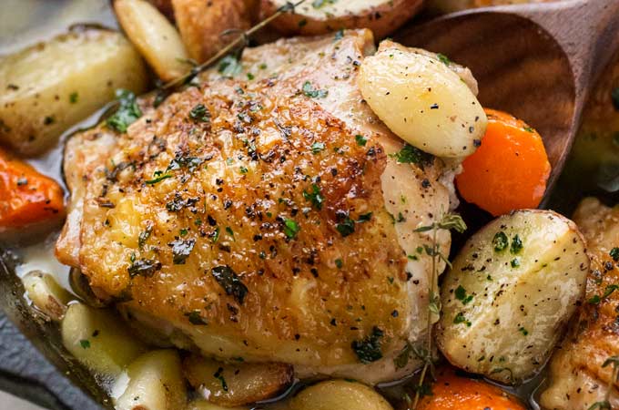 One Pan Roasted Chicken and 40 Cloves of Garlic | Chicken thighs are roasted with garlic, herbs, white wine, potatoes and carrots for an incredibly flavorful one pan meal! | The Chunky Chef | #dinnerrecipe #chicken #roasted #onepan #onepot #easyrecipe