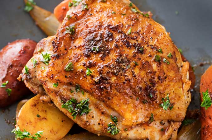 This slow cooker Harissa chicken is absolutely brimming with bold, spicy flavors!  Chicken thighs, potatoes, carrots, and onion are slathered in a rich spice mix and then made easily in the crockpot! | #slowcooker #crockpot #chickenrecipes #harissa #weeknightmeal