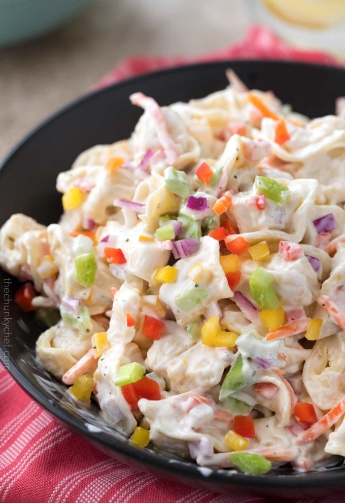 Brightly colored rainbow tortellini salad in black bowl