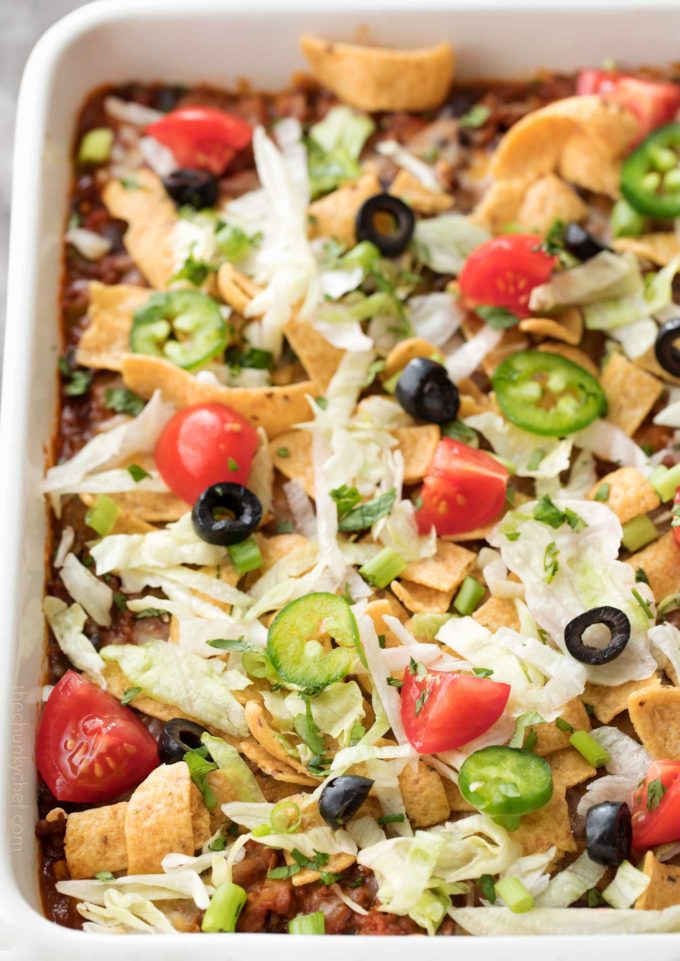 Taco casserole in white baking dish with toppings