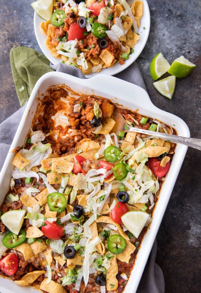 Taco casserole in white baking dish with serving spoon