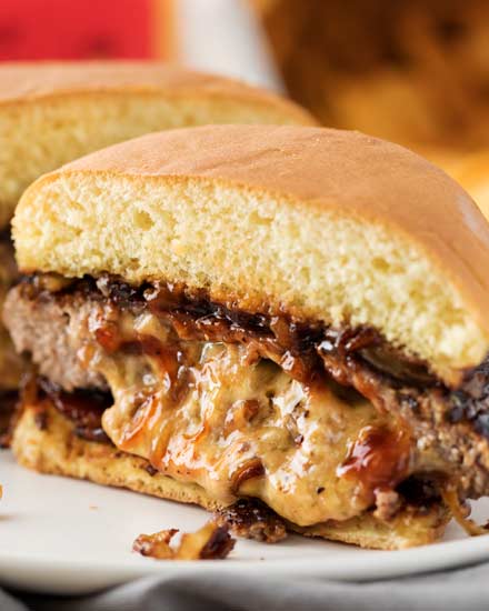 This classic Juicy Lucy burger is a well known Midwestern recipe.  Definitely not your average cheeseburger, this burger recipe is stuffed with caramelized onions and cheddar cheese!  Our favorite version also includes crispy bacon and smoky bbq sauce! #burger #cheeseburger #juicylucy #cheddar #baconcheeseburger #stuffed #summerbbq