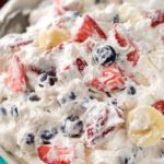 This simple 5 ingredient cheesecake salad is loaded with fresh berries, bananas, and a creamy no bake cheesecake filling! #cheesecakesalad #redwhiteandblue #4thofjuly #summerfood #fruitsalad #nobakedessert #dessertrecipe