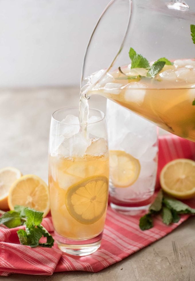 Pouring iced green tea into glass with lemon slice