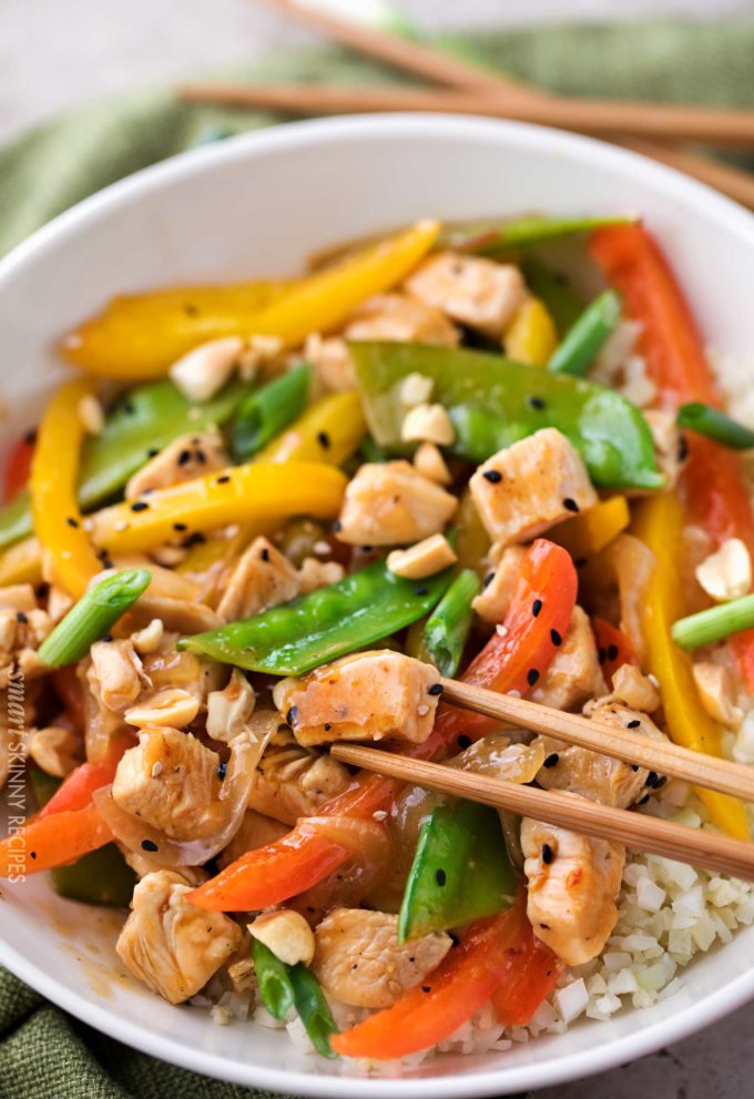 Chopsticks grabbing a piece of Szechuan chicken stir fry