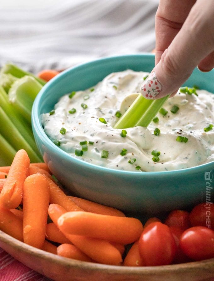 Celery dipping into veggie dip in bowl