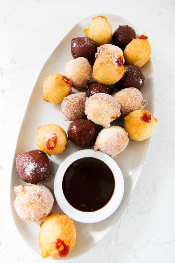 Variety of donut holes on white plate with chocolate sauce