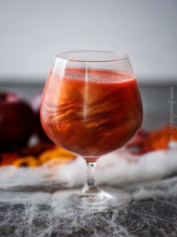 Perfect for Fall and Halloween, this sweet and eerily beautiful cocktail is made with just a handful of ingredients, and tastes every bit as great as it looks! #cocktail #drink #applecider #Halloween #Fall #falldrink #drinks #lusterdust #viniq 