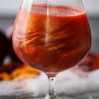 Perfect for Fall and Halloween, this sweet and eerily beautiful cocktail is made with just a handful of ingredients, and tastes every bit as great as it looks! #cocktail #drink #applecider #Halloween #Fall #falldrink #drinks #lusterdust #viniq