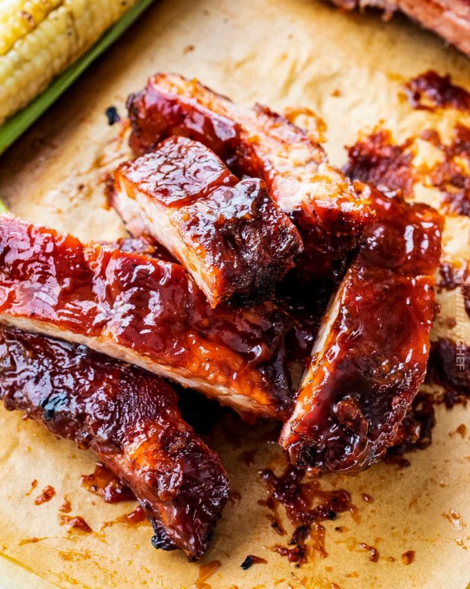 Delicious homemade smoked ribs are easier to make than you think, especially using the popular 3-2-1 method.ย Fall of the bone tender, and lip-smackingly good, these ribs are FABULOUS!! #ribs #pork #bbq #smoked #smoking #grilling #easyrecipe Pile of smoked baby back ribs on parchment paper