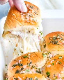 The ultimate party or finger food, these melt in your mouth ham and cheese sliders are made savory with the addition of garlic and herbs, drizzled in a garlic/shallot butter and baked until tender and golden! #appetizer #partyfood #fingerfood #sliders #hamandcheese #garlicandherb #easyrecipe