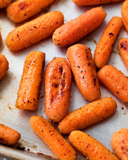 These simple roasted carrots are made easily on a sheet pan, with a simple roasting method that brings out the natural sweetness of the baby carrots.  They're the perfect side dish!  #roasted #carrots #sidedish #holidayrecipe #carrotrecipe #sheetpan #healthy #side #thanksgiving