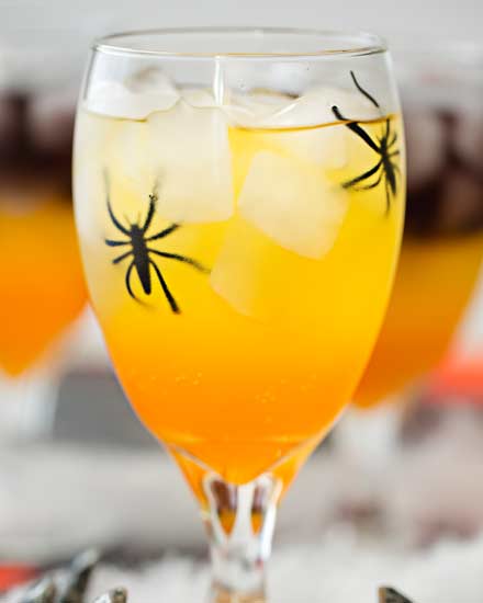 This non-alcoholic Halloween party punch is layered to resemble candy corn, with plastic spiders added for a fun spooky effect! #punch #party #trickortreat #halloween #nonalcoholic #drinkrecipe #mocktail