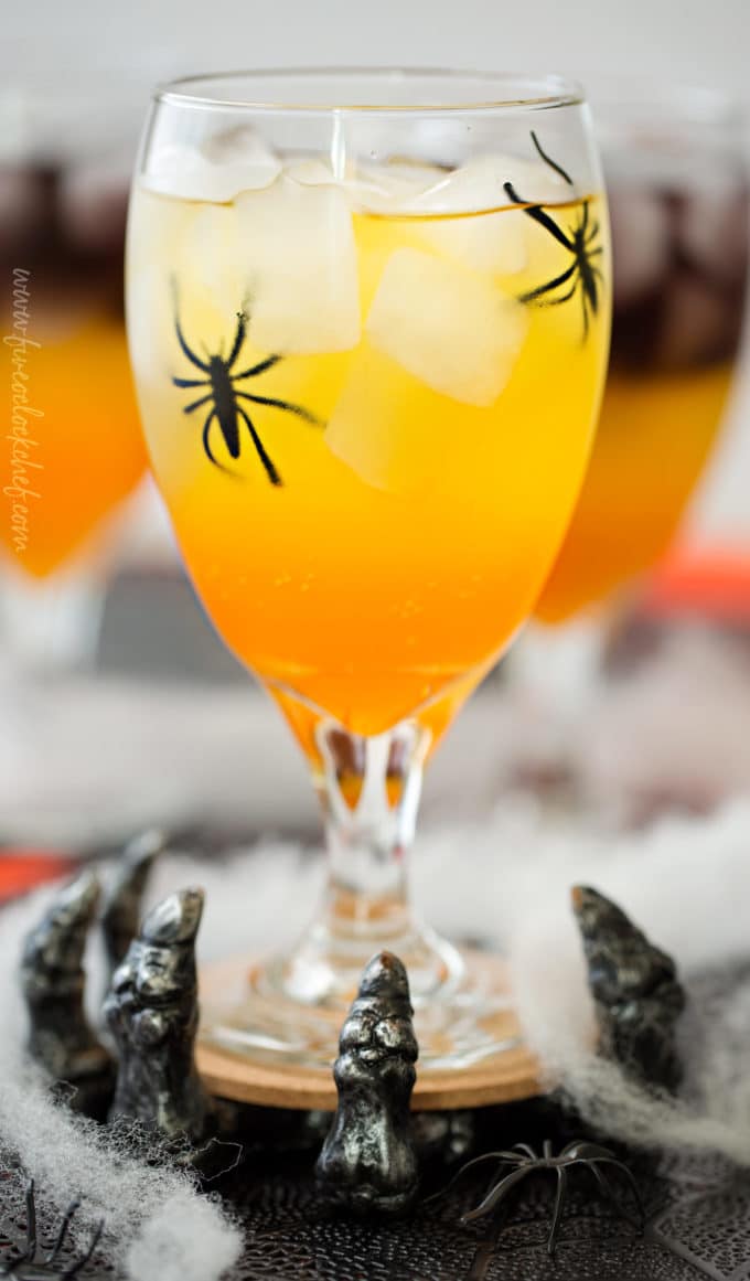 This non-alcoholic Halloween party punch is layered to resemble candy corn, with plastic spiders added for a fun spooky effect! #punch #party #trickortreat #halloween #nonalcoholic #drinkrecipe #mocktail