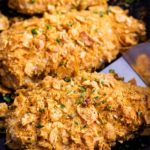 Crunchy, juicy baked chicken made by slathering chicken breasts in ranch dressing then coating in seasoned cornflakes.  All the satisfying crunch of fried chicken, but with less fat and more flavor! #chicken #cornflake #baked #easyrecipe 