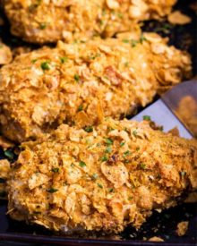 Crunchy, juicy baked chicken made by slathering chicken breasts in ranch dressing then coating in seasoned cornflakes. All the satisfying crunch of fried chicken, but with less fat and more flavor! #chicken #cornflake #baked #easyrecipe