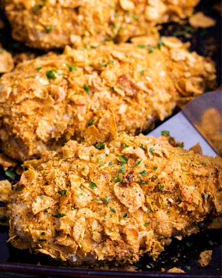 Crunchy, juicy baked chicken made by slathering chicken breasts in ranch dressing then coating in seasoned cornflakes.  All the satisfying crunch of fried chicken, but with less fat and more flavor! #chicken #cornflake #baked #easyrecipe 