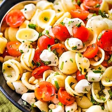 Caprese pasta salad made with tomatoes, marinated fresh mozzarella cheese, fresh basil, and a mouthwatering homemade Italian herb vinaigrette! #pastasalad #caprese #tomatobasil #italian #sidedish #potluck #bbq #summer